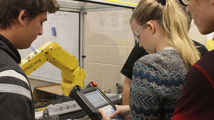male and female students working on a robotic control arm.